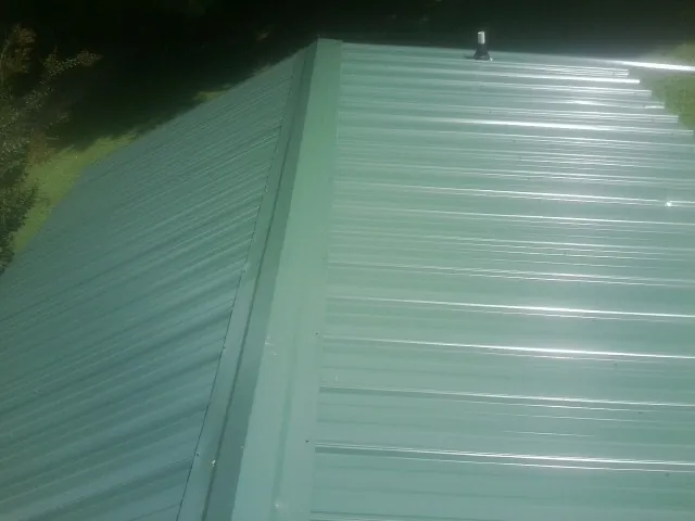 New green metal panels meeting at the ridge of a roof — Flat Roof Repair work by our crew in Mill Creek
