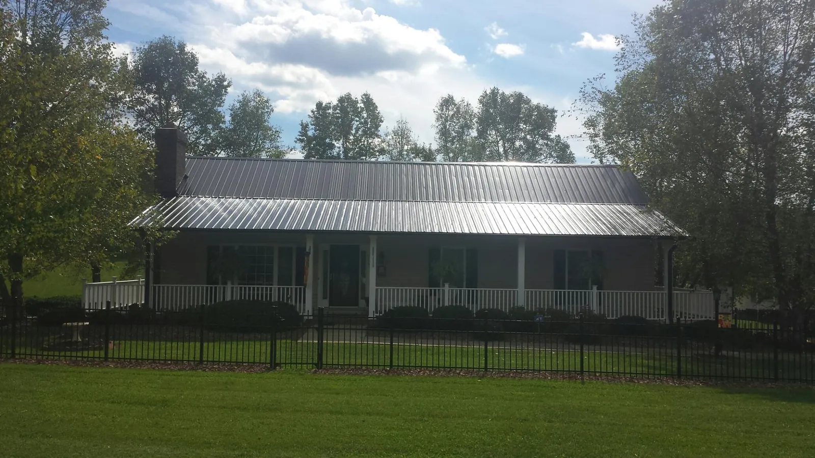 Gray metal roof on a brick ranch with a full width front porch — Gutter Guard Installation work by our crew in Mill Creek